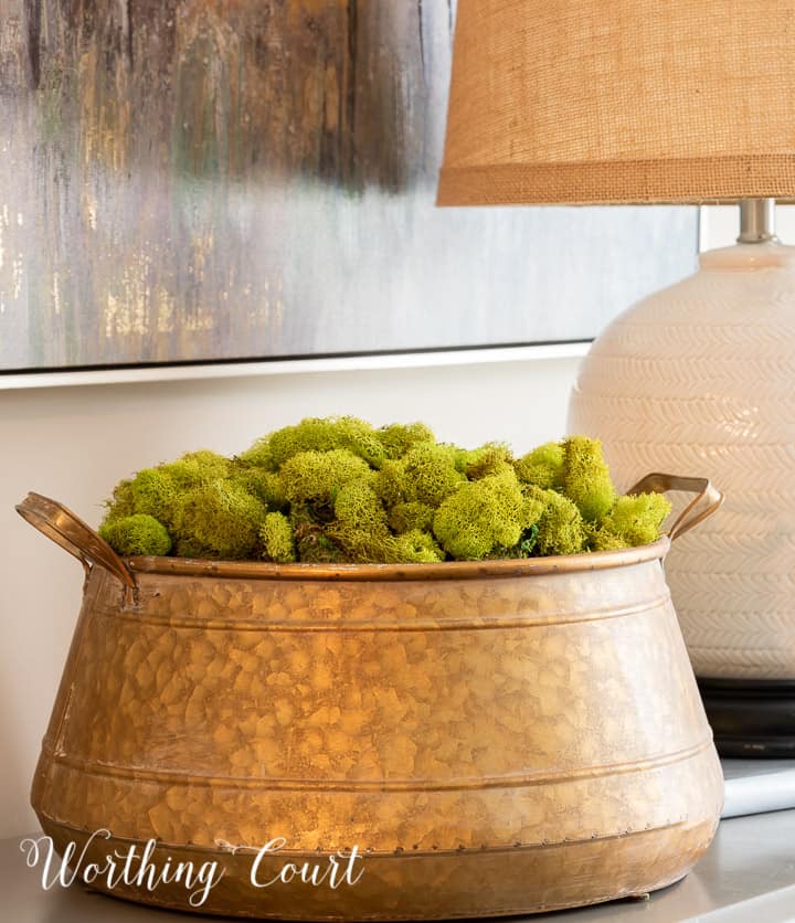 brass bowl filled with green moss on a small chest