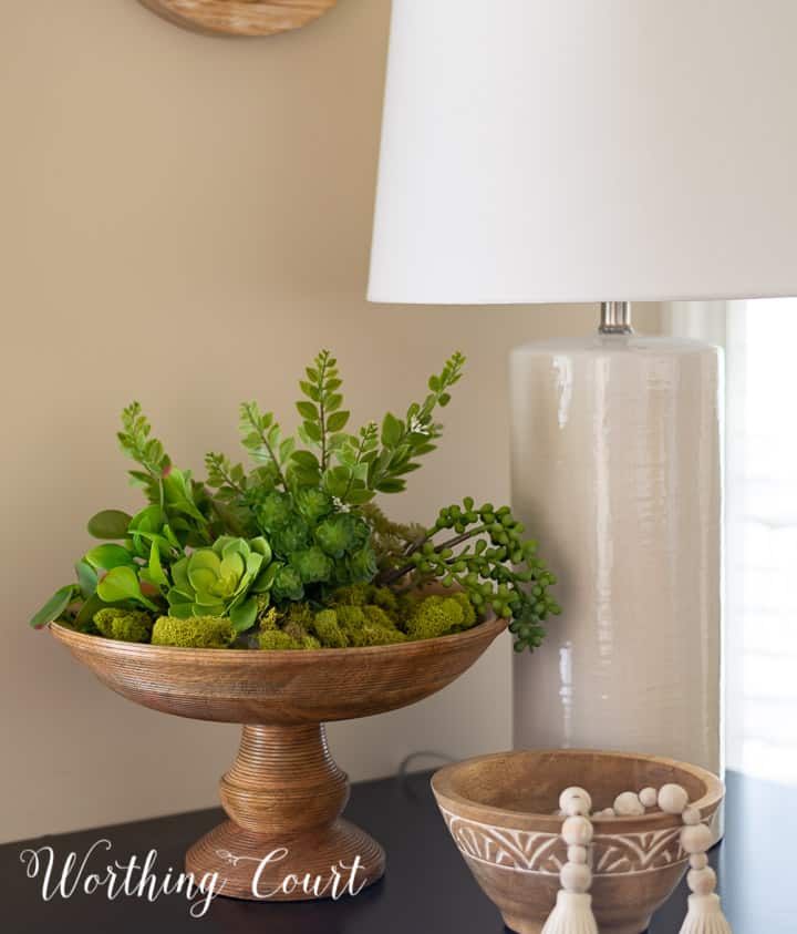 wooden pedestal bowl filled with green moss and faux succulents