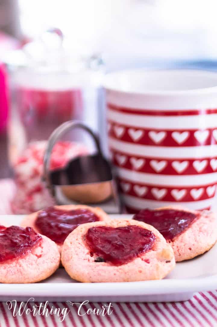 strawberry cookies on a white plate staged with other red and white items for Valentine's Day