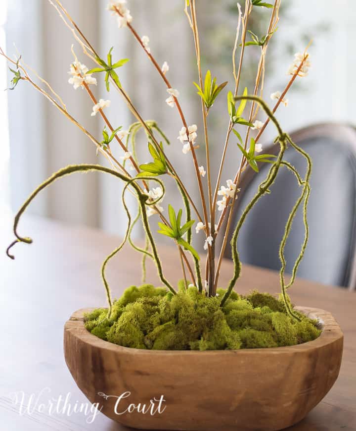 wood bowl filled with green moss and tall faux greenery