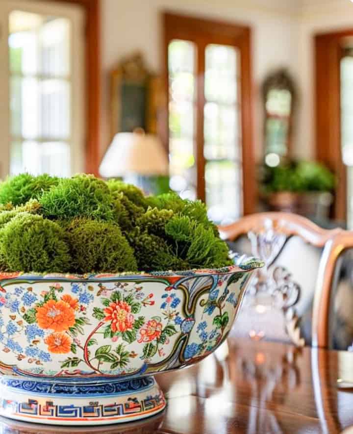 colorful chinoiserie bowl filled with moss on a dining room table