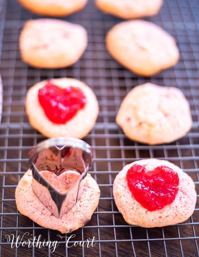 heart shaped cookie cutter on top of strawberry cookies on a cooling rack