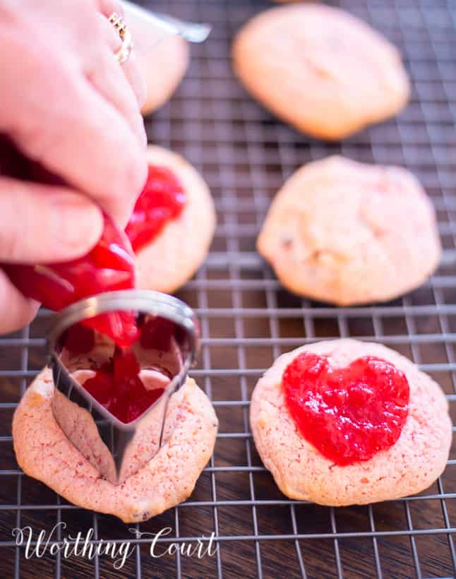 adding strawberry preserves to strawberry cookies on a cooling rack