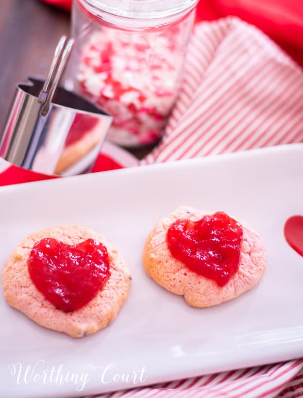 strawberry cookies on a white plate staged with other red and white items for Valentine's Day