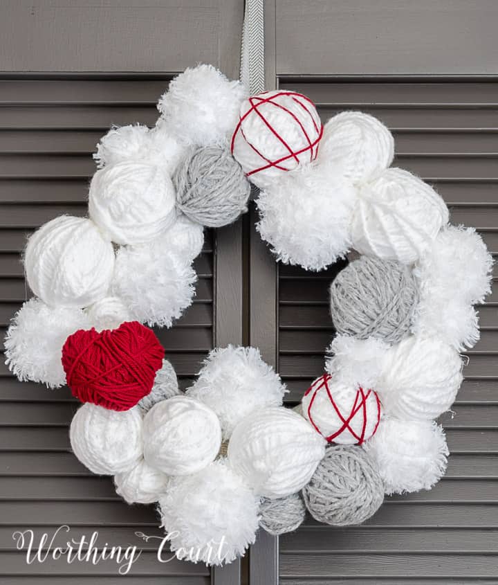 Valentine's Day wreath made with styrofoam balls covered with white and gray yarn and a heart cutout wrapped with red yarn