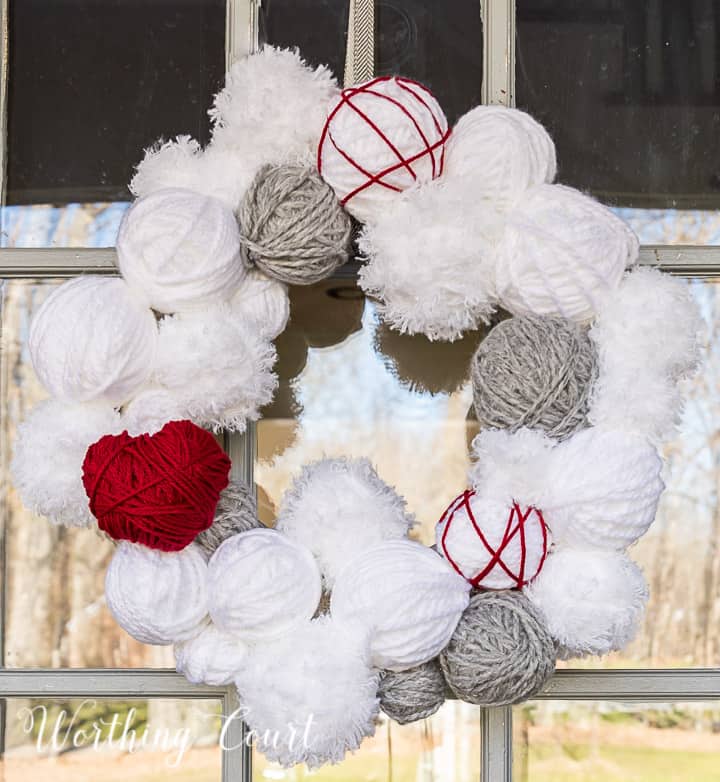 Valentine's Day wreath made with styrofoam balls covered with white and gray yarn and a heart cutout wrapped with red yarn