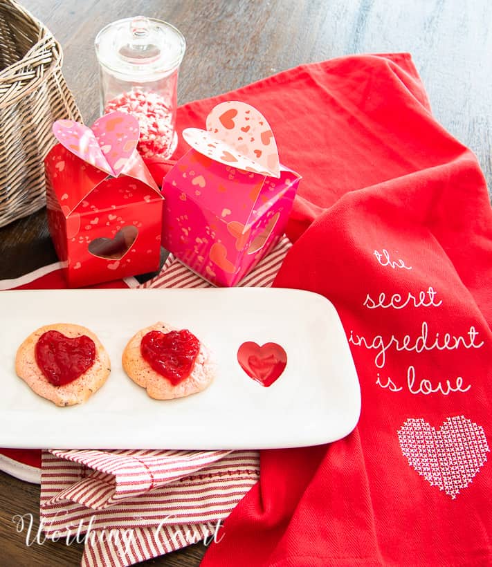 strawberry cookies on a white plate staged with other red and white items for Valentine's Day