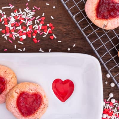 strawberry cookies on a white plate surrounded with red, white and pink sprinkles