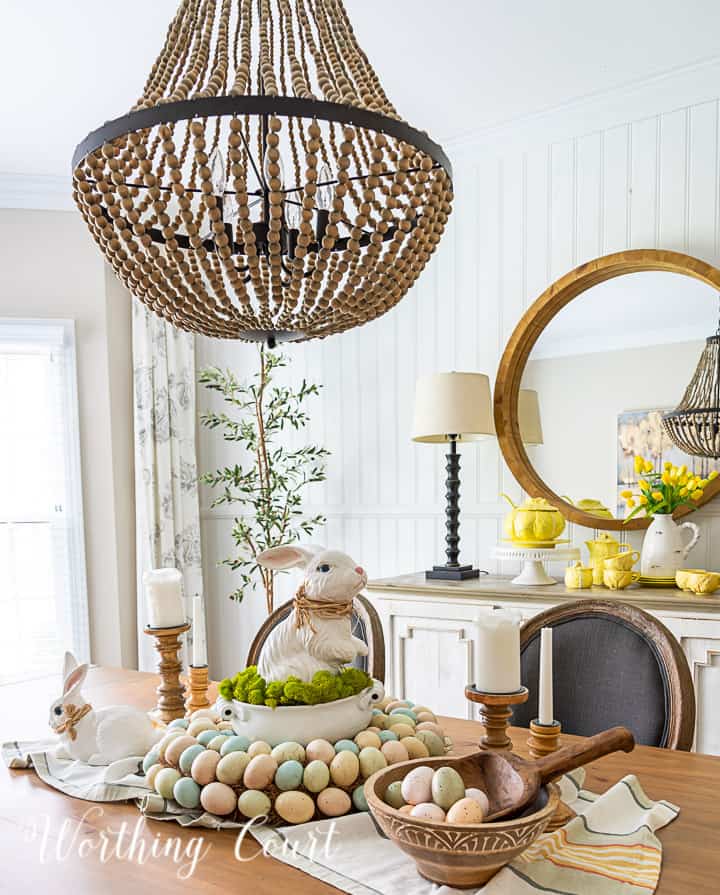 Easter centerpiece with white ceramic bunny in the middle of an egg wreath and a wood bowl filled with faux Easter eggs