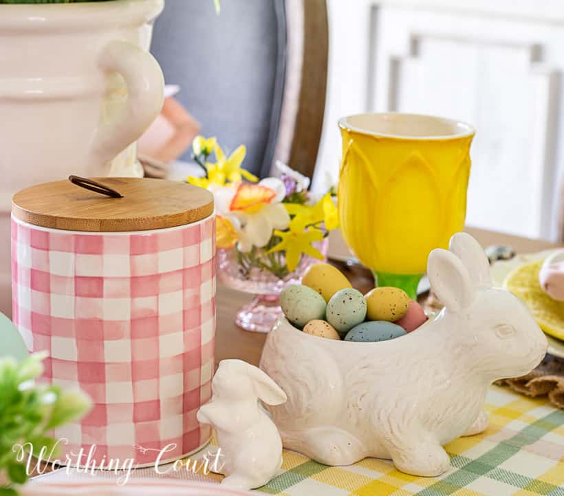 Portion of an Easter tablescape using yellow dishes and faux flowers