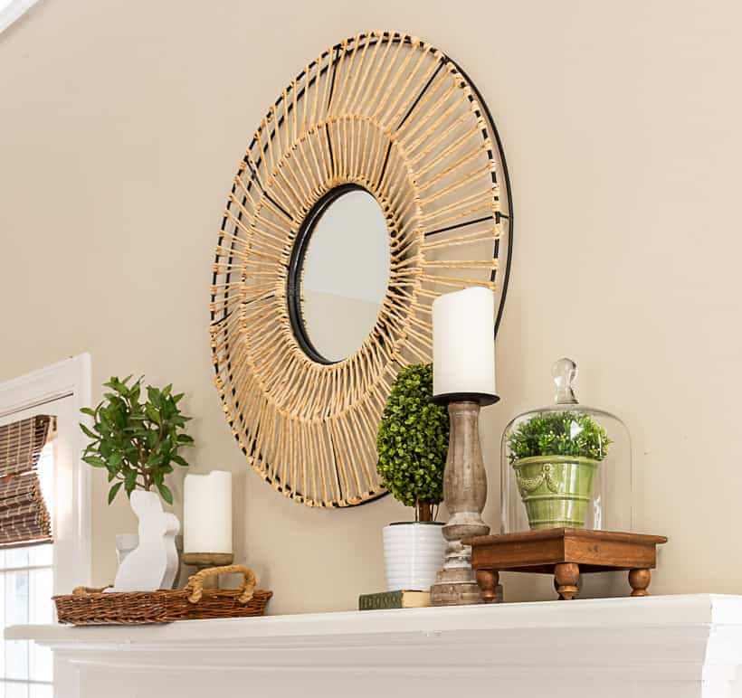 fireplace mantle with a round mirror above and spring decorations on each end