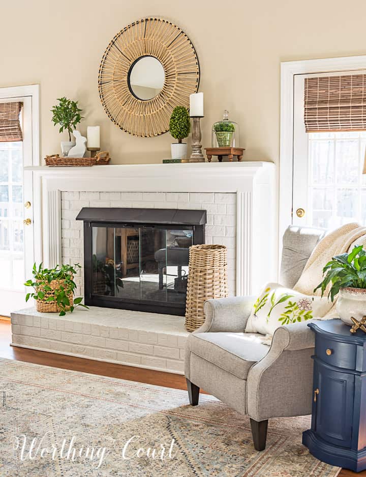 gray chair beside white fireplace with spring decorations on the mantle