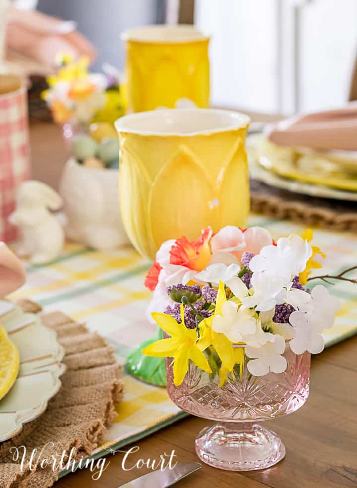 Portion of an Easter tablescape using yellow dishes and faux flowers