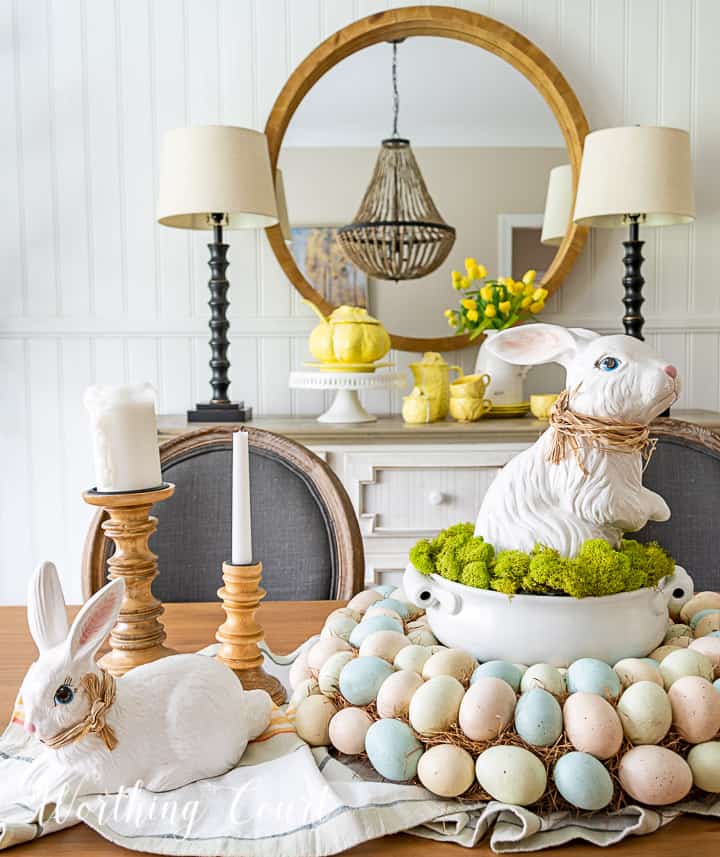Easter centerpiece with white ceramic bunny in the middle of an egg wreath and a wood bowl filled with faux Easter eggs