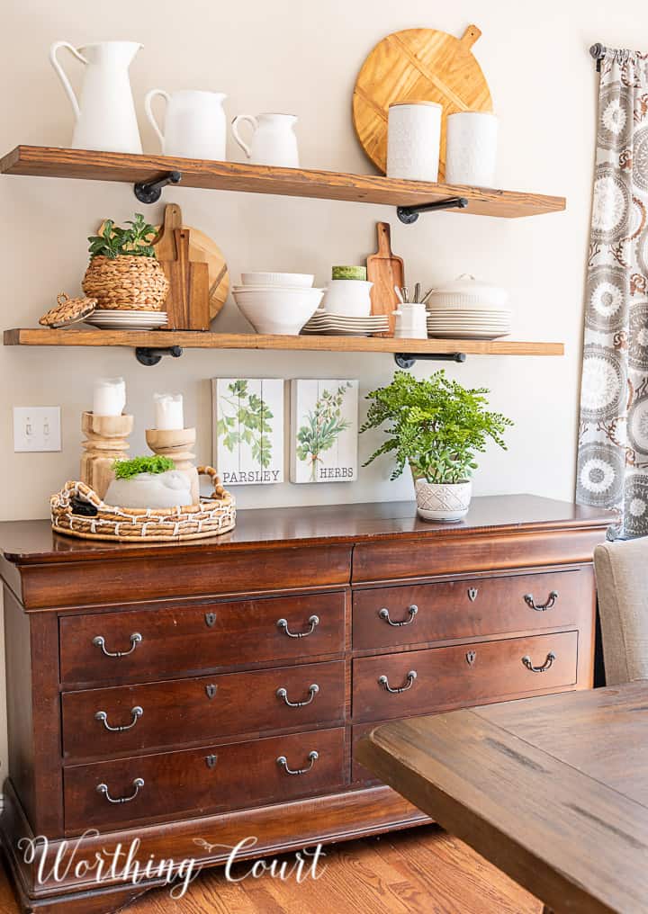 open wood shelves decorated with white dishes, greenery and light wood toned accessories