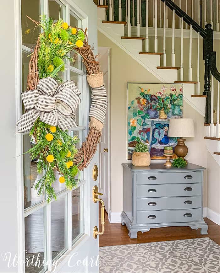 view of spring decor looking through a front door with a wreath hanging on it