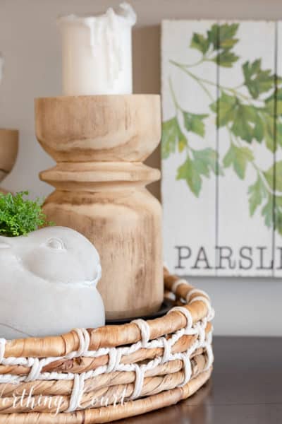 vignette with wood candlesticks and a concrete bunny in a round basket tray