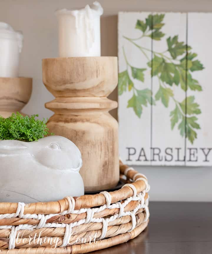 vignette with wood candlesticks and a concrete bunny in a round basket tray