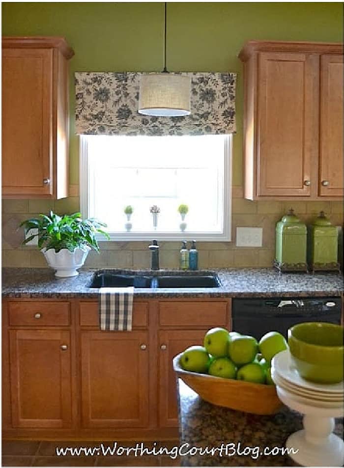 window and cabinets in a kitchen with green walls