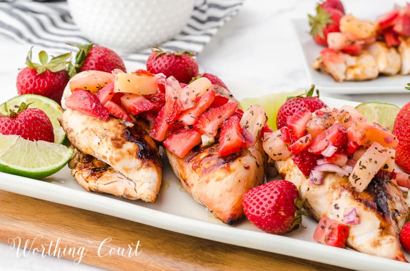 platter of sliced grilled chicken breast topped with strawberry and pineapple salsa