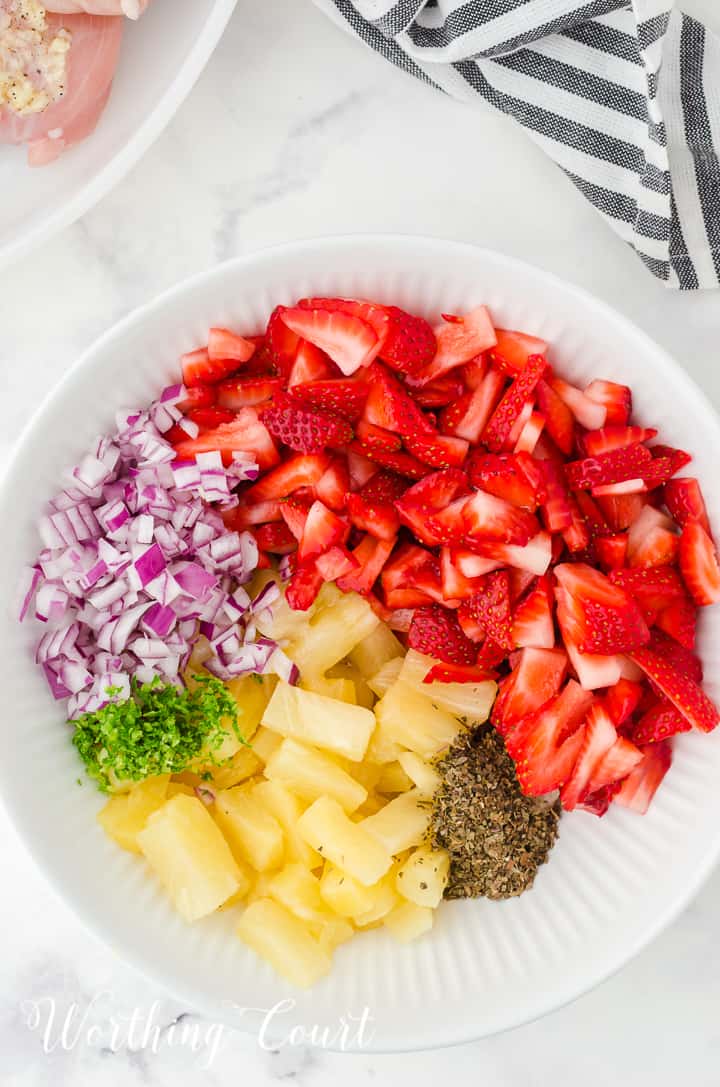 ingredients for strawberry and pineapple salsa in a white bowl