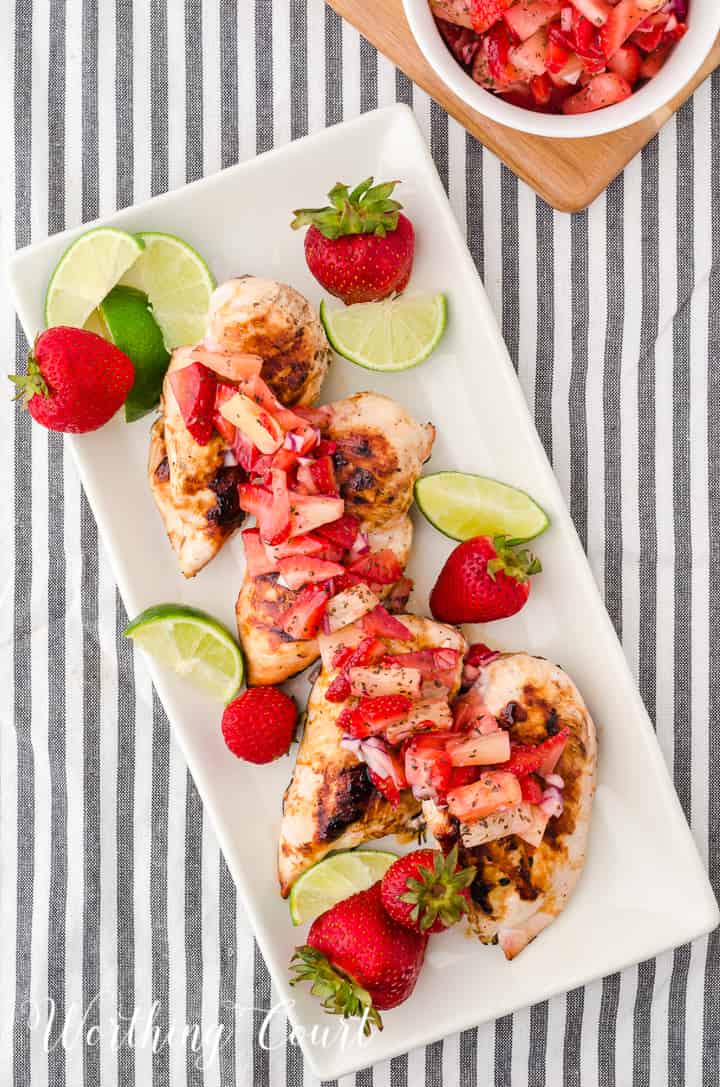 platter of sliced grilled chicken breast topped with strawberry and pineapple salsa