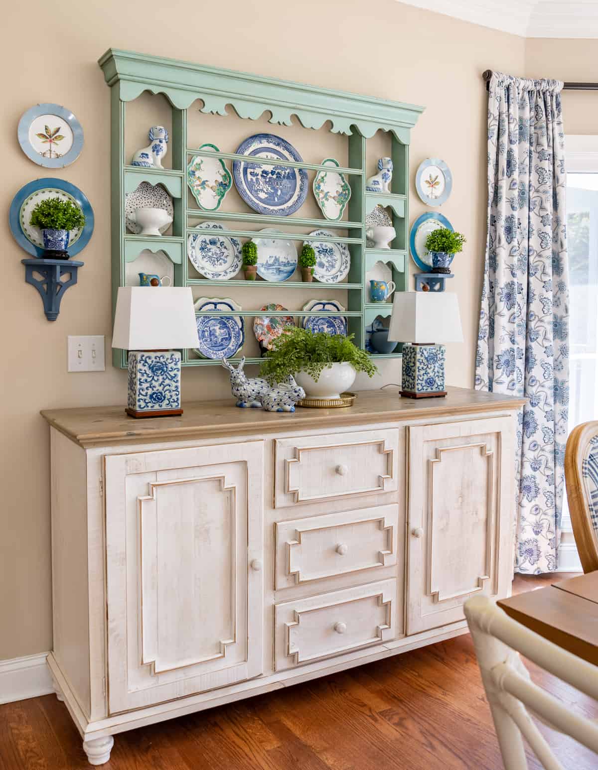 beige walls with blue plate rack filled with blue and white spring decor above a white sideboard