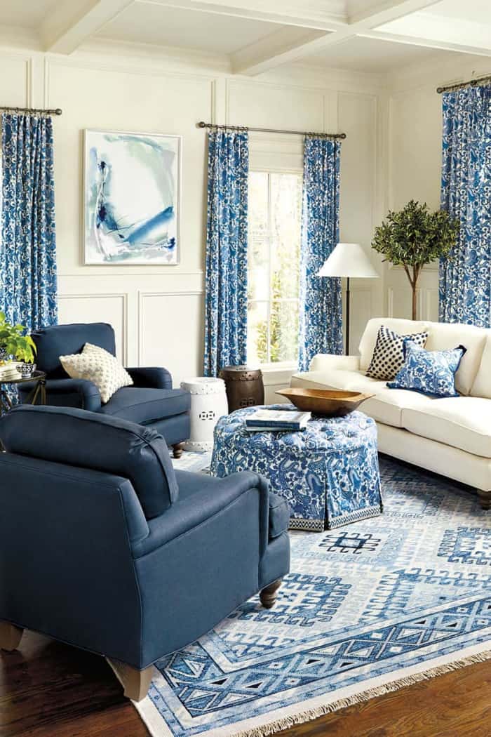 living room with blue and white furniture, rug, draperies and accessories