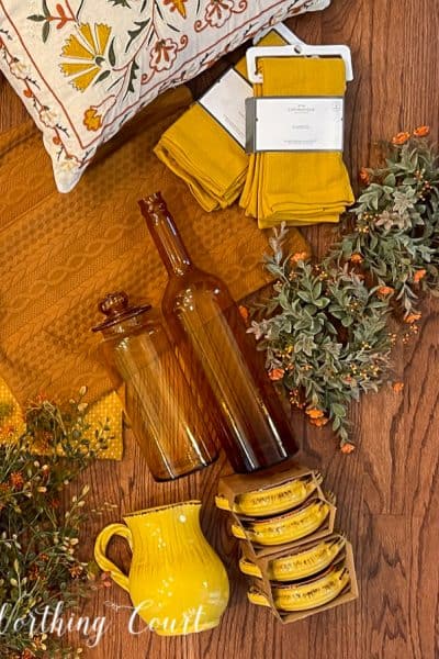 overhead view of amber jars, yellow napkins, fall foliage and yellow dishes laying on a hardwood floor