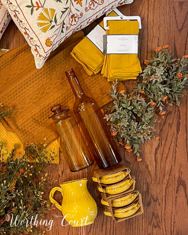 overhead view of amber jars, yellow napkins, fall foliage and yellow dishes laying on a hardwood floor