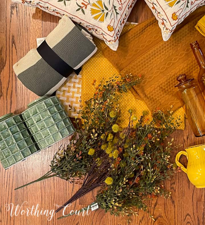 overhead view of pair of green urns, fall foliage, striped throw and yellow pillow covers on a hardwood floor