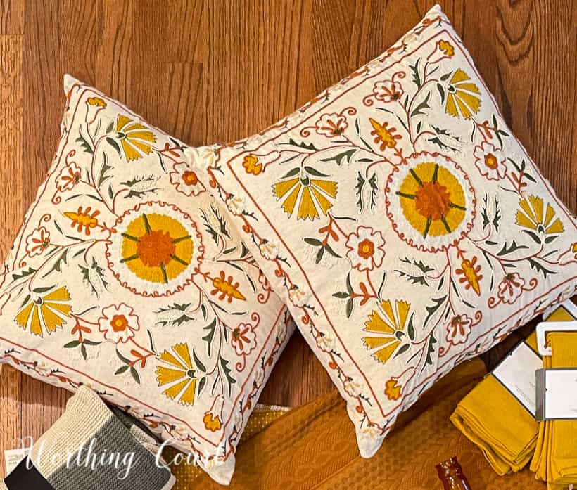 pair of pillows embroidered with yellow, green and deep orange on a cream background