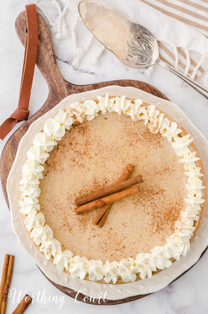 whole gingerbread cheesecake garnished with whipped cream and cinnamon sticks