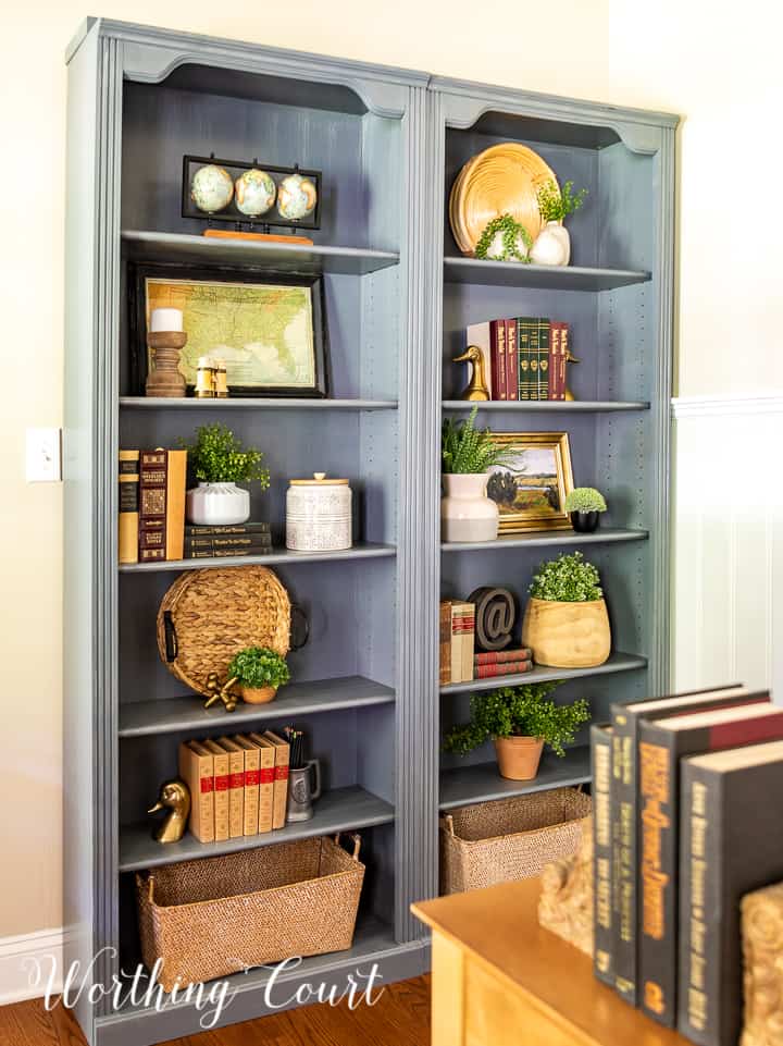 pair of gray bookcases filled with a variety of updated traditional accessories