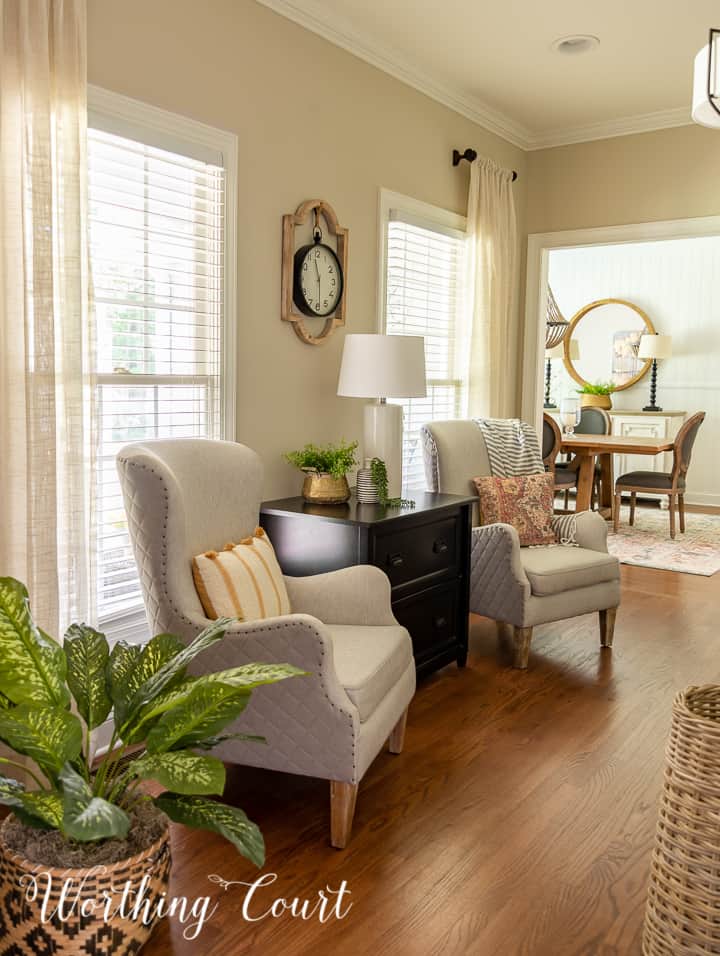 pair of club chairs in a home office with a view into the dining room