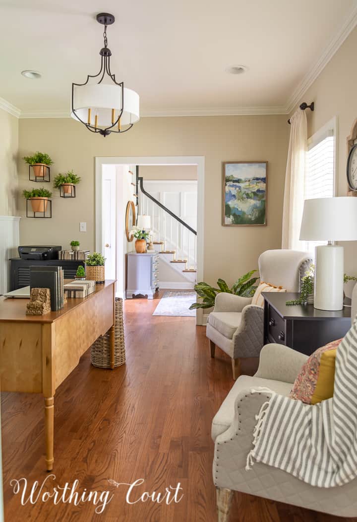 view into home office with two club chairs, natural wood toned desk and abstract wall art