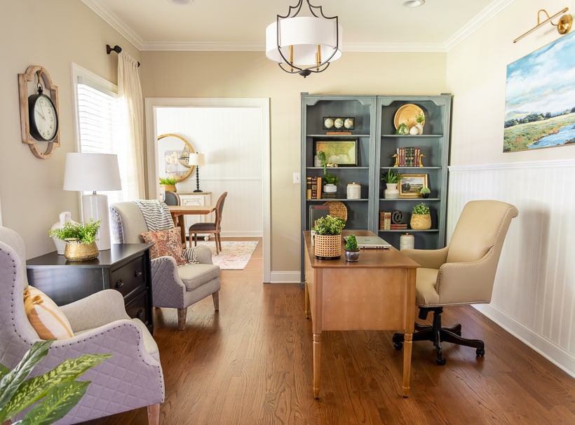 view into home office with desk, bookcases and armchairs