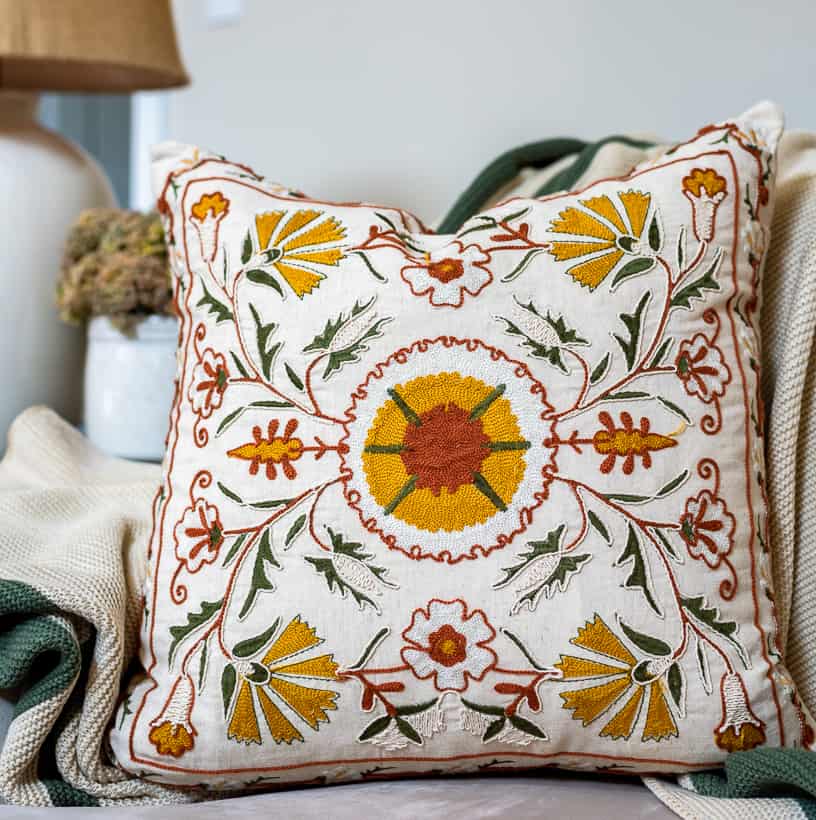 embroidered pillow with yellow, green and deep orange on a cream background