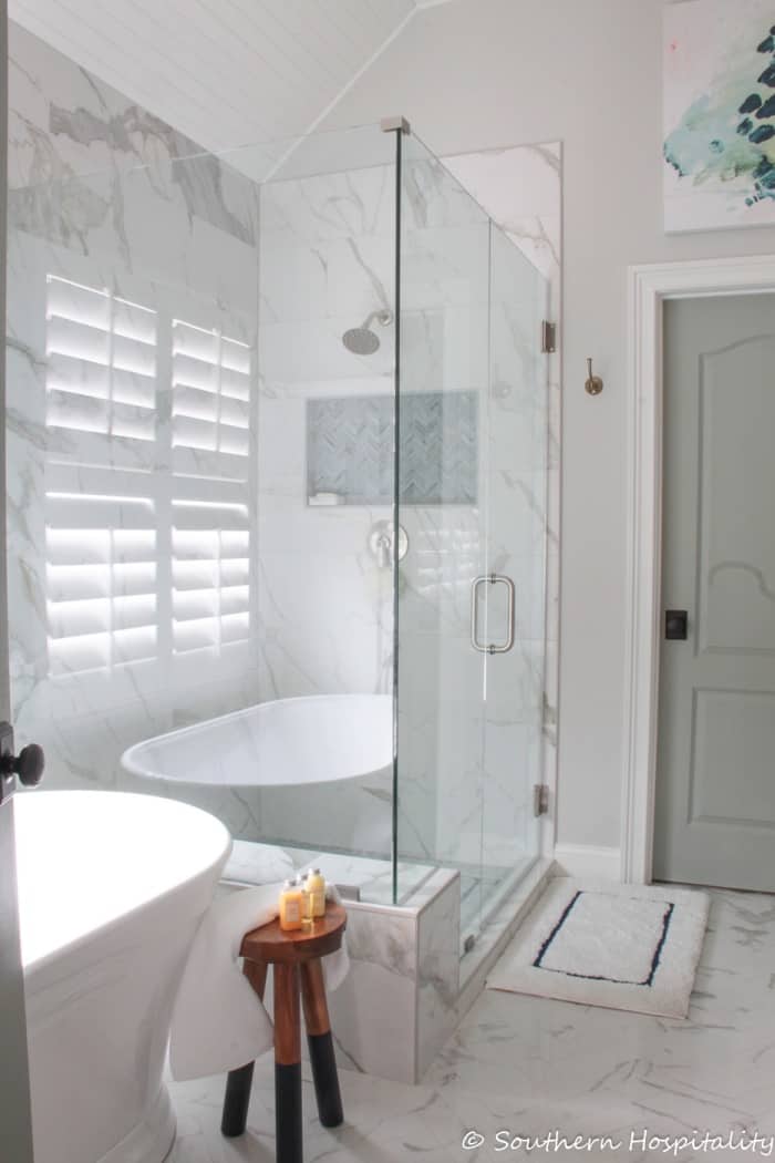 renovated bathroom with white and gray tile, glass shower and white free standing tub