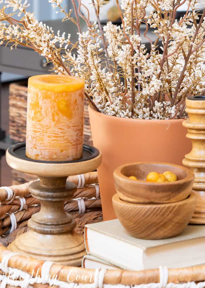 fall vignette in a basket tray with wood accents, terra cotta pot, candle and dried stems