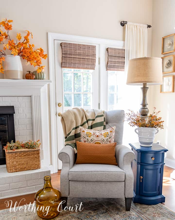 gray chair in front of windows beside white fireplace with fall decor