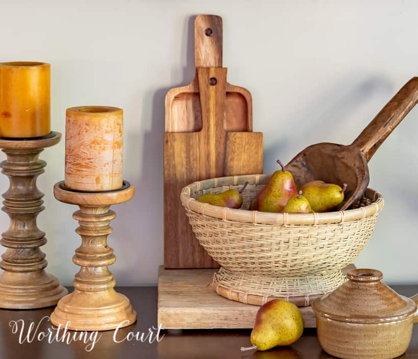 woven pedestal bowl filled with faux pears in front of cutting boards