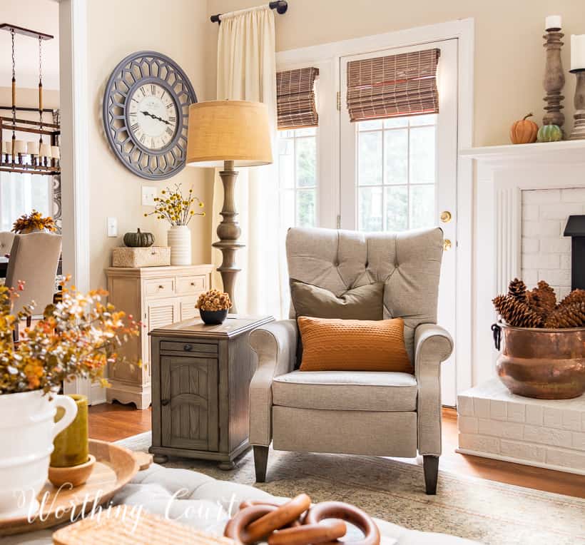 gray chair in front of windows beside white fireplace with fall decor