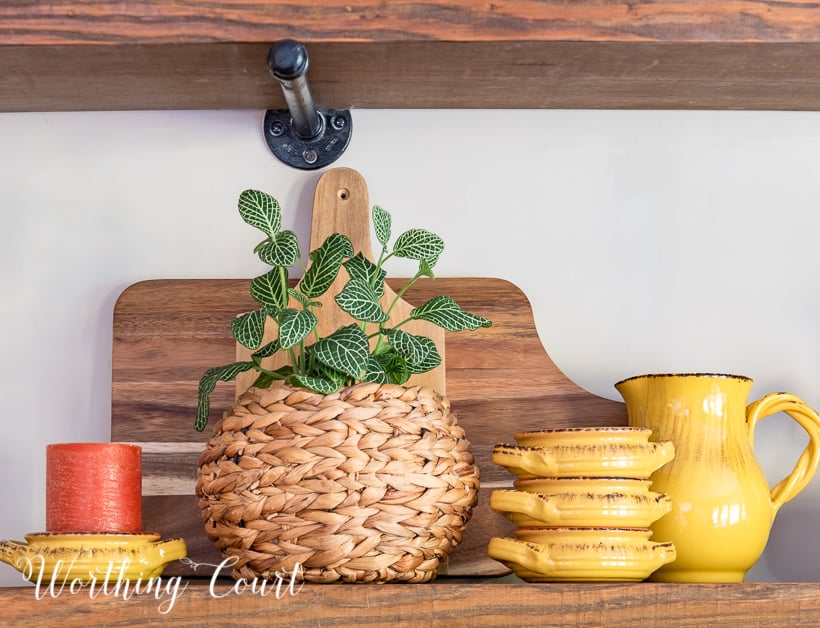 wooden open shelves decorated for fall with rich amber and green accessories