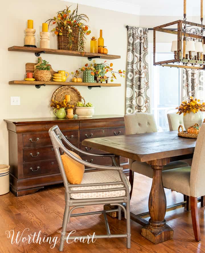 dining area with open shelves above a sideboard decorated for fall