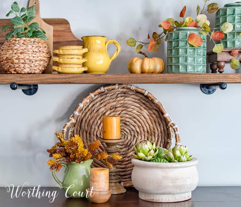 wooden open shelves decorated for fall with rich amber and green accessories