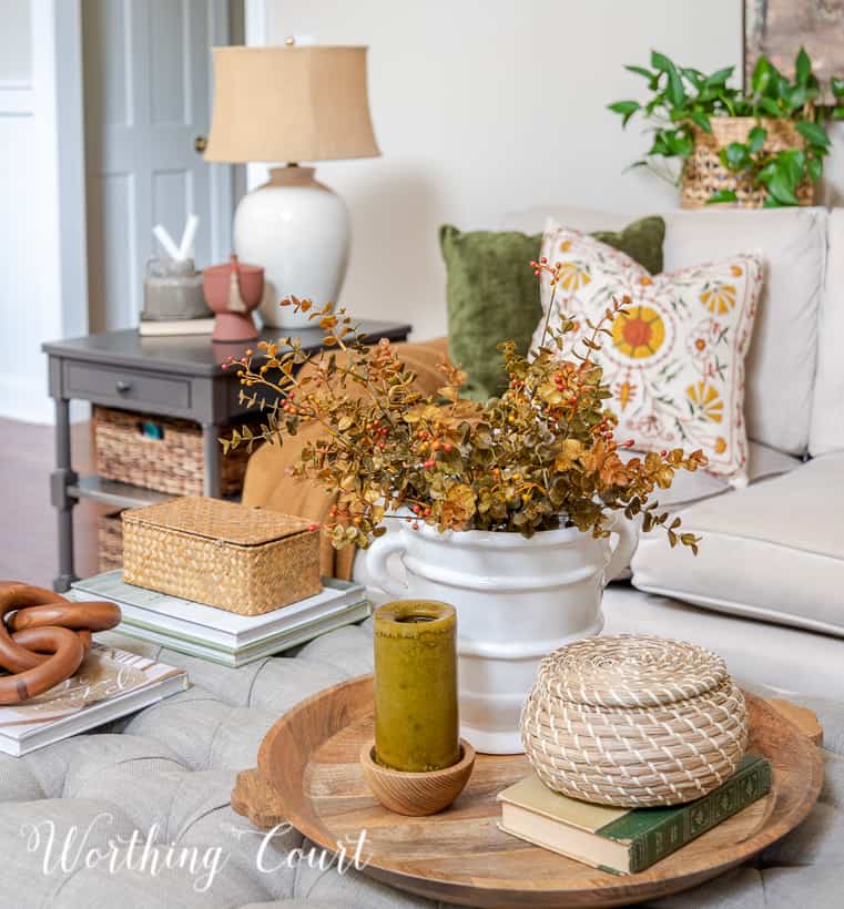 fall vignette on upholstered coffee table in front of neutral covered couch with fall pillows