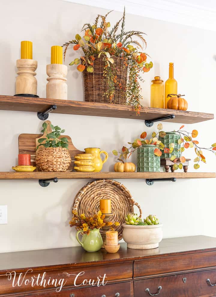 wooden open shelves decorated for fall with rich amber and green accessories