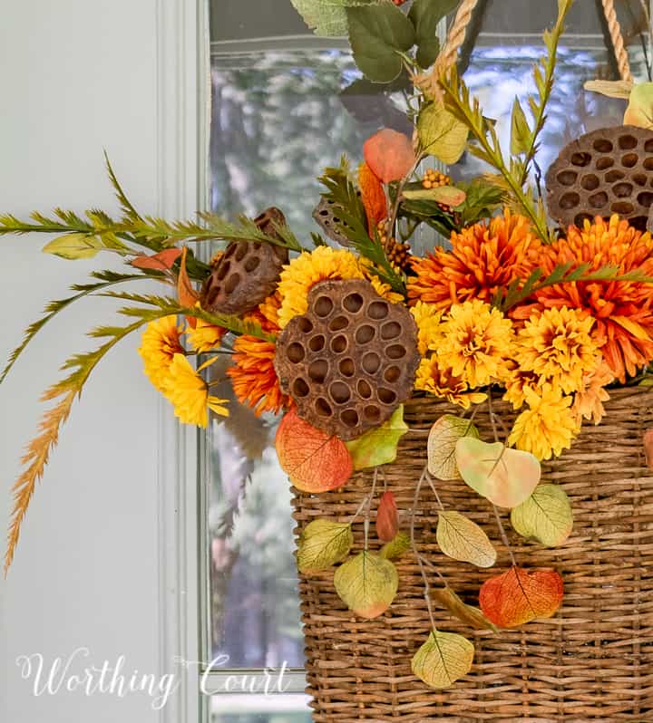 handing basket on gray front door filled with fall colored faux stems