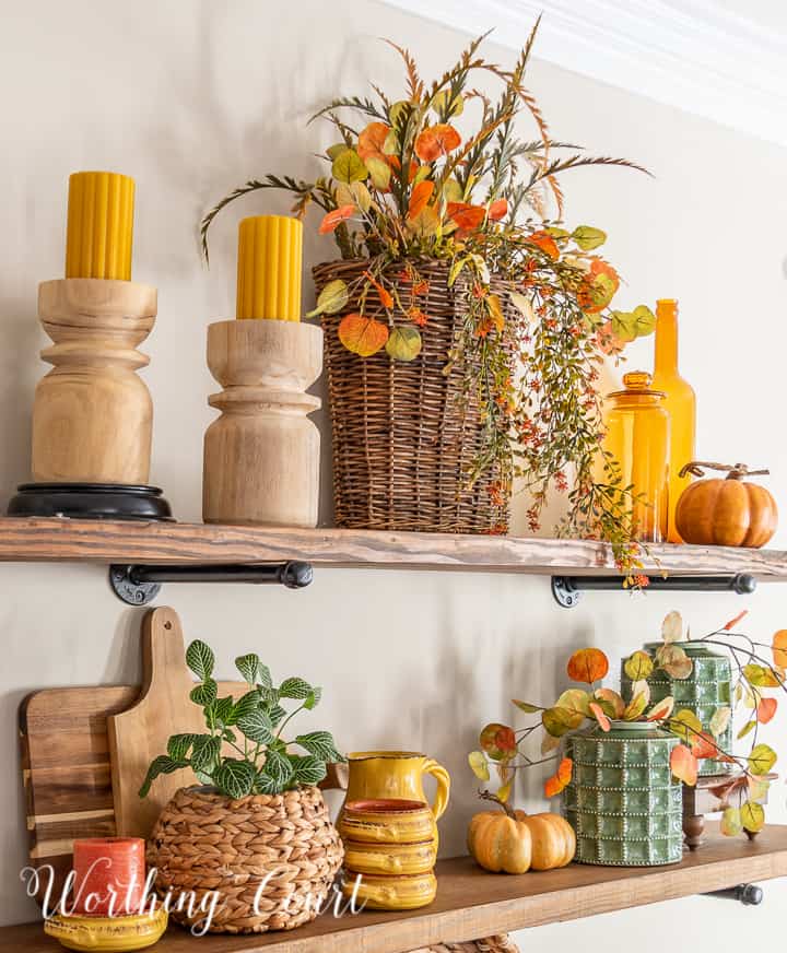 wooden open shelves decorated for fall with rich amber and green accessories